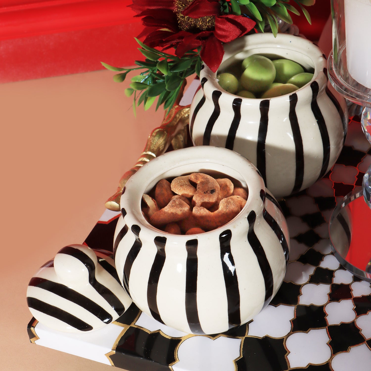 This gifting tray comes with 1 glass candle holder adorned with red flowers &amp; 4 ceramic abstract print jars filled with Oreo almonds , chocolate raisins, Pista flavored Cashew and Munchy masala cashew decorated in our MDF tray.